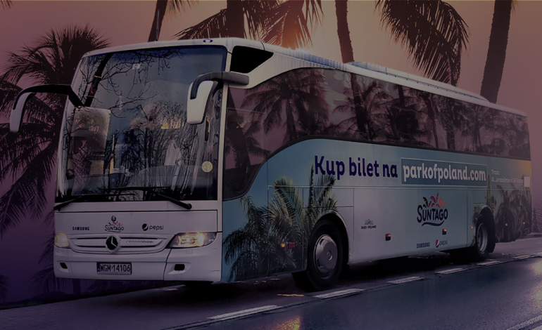 Autobus Suntago, ozdobiony grafiką z palmami. Na boku autobusu widoczny napis &quot;Kup bilet na parkofpoland.com&quot;. W tle sylwetki palm i zachodzące słońce